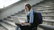woman sitting on concrete stairs using laptop